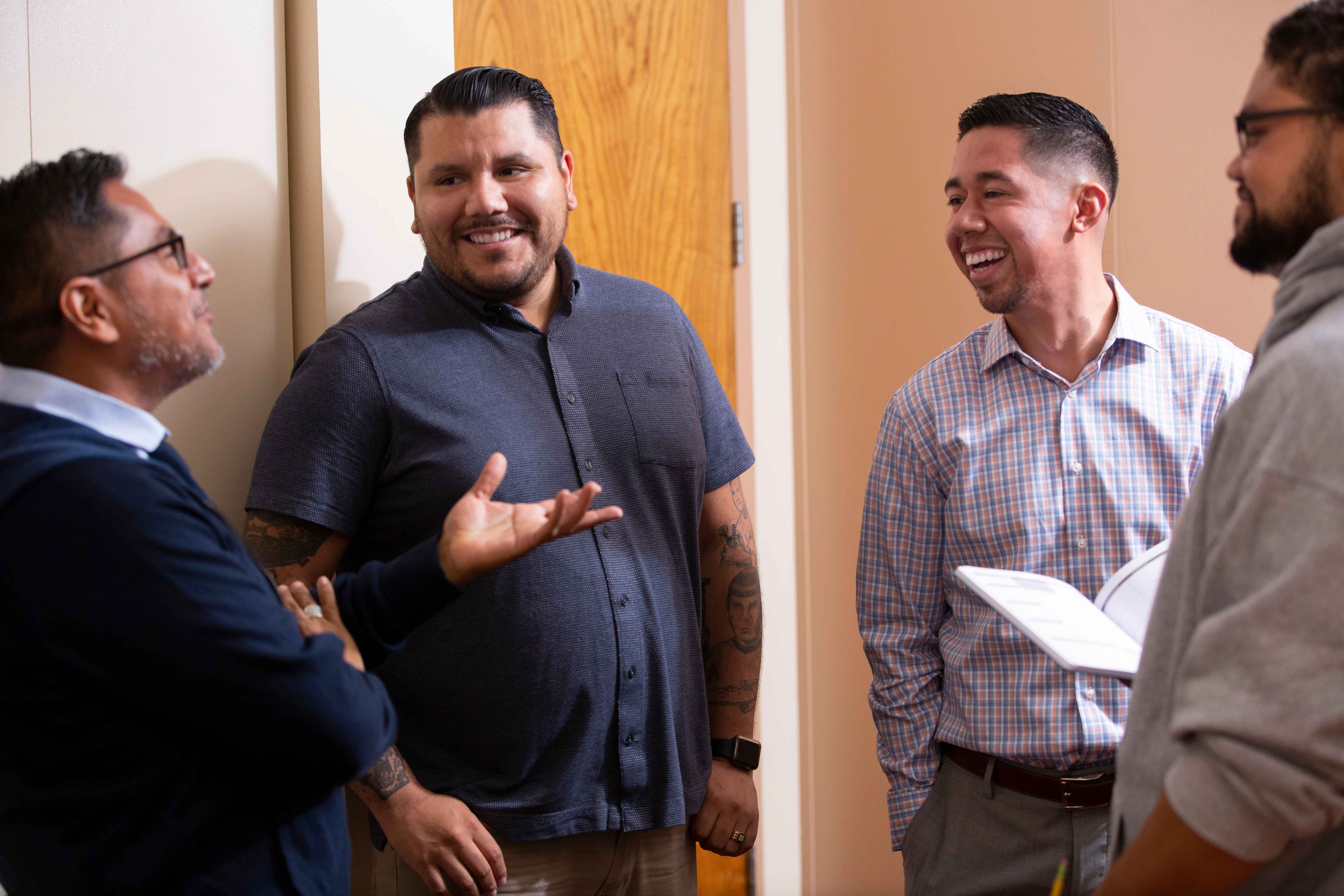 4 men standing together talking and smiling