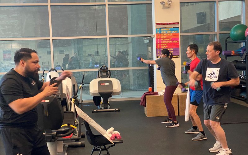 Faculty and staff members participate in an exercise class in a gym that is led by a graduate student