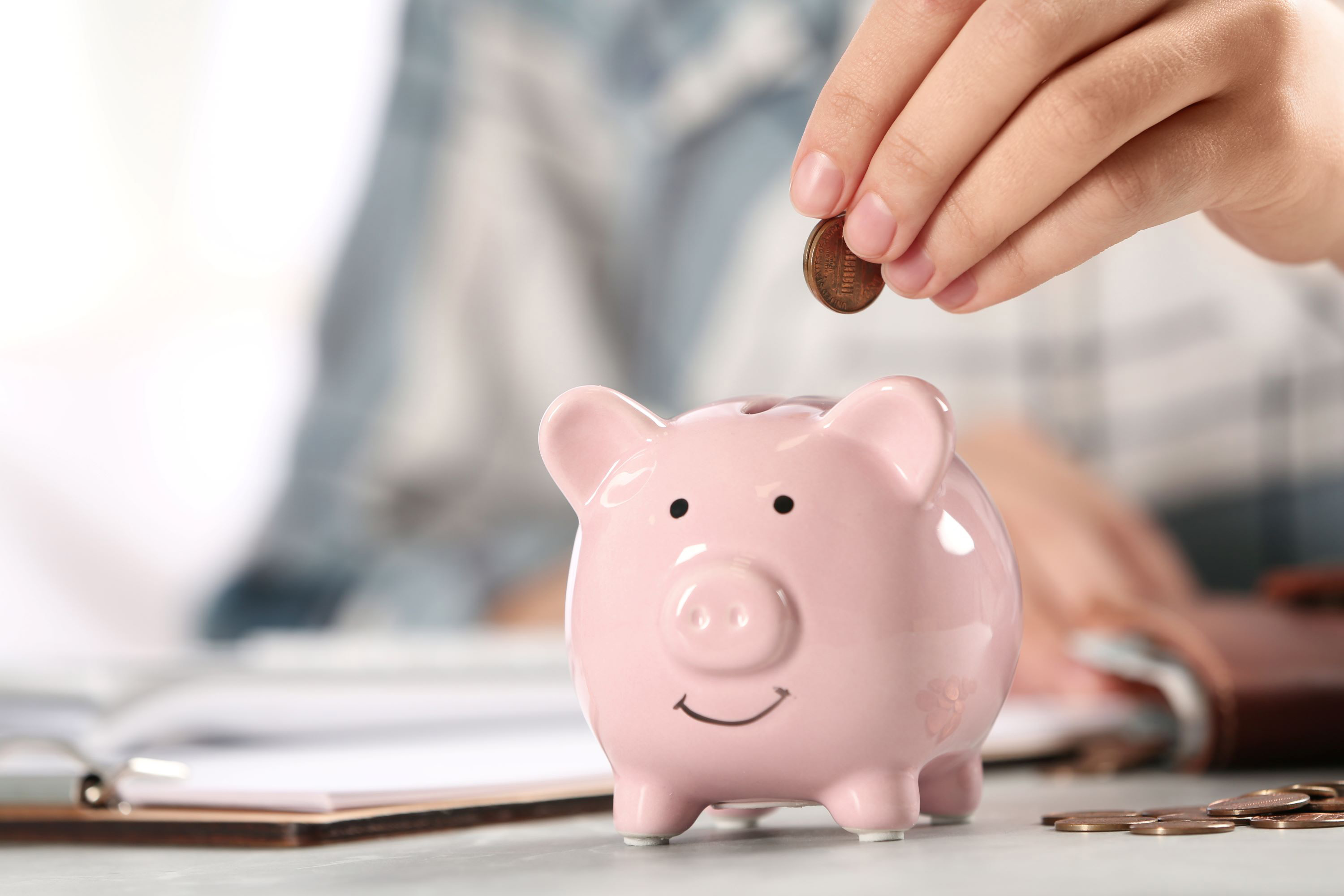 a person dropping a penny into a piggy bank