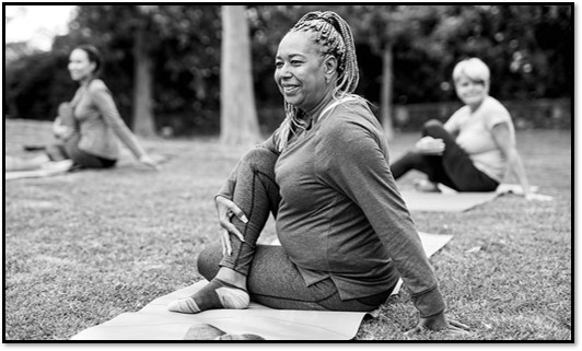 Three people practicing yoga in a park, focused on a woman doing a seated twist.