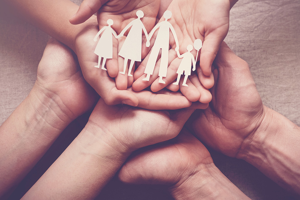 many hands holding paper cutout of a family