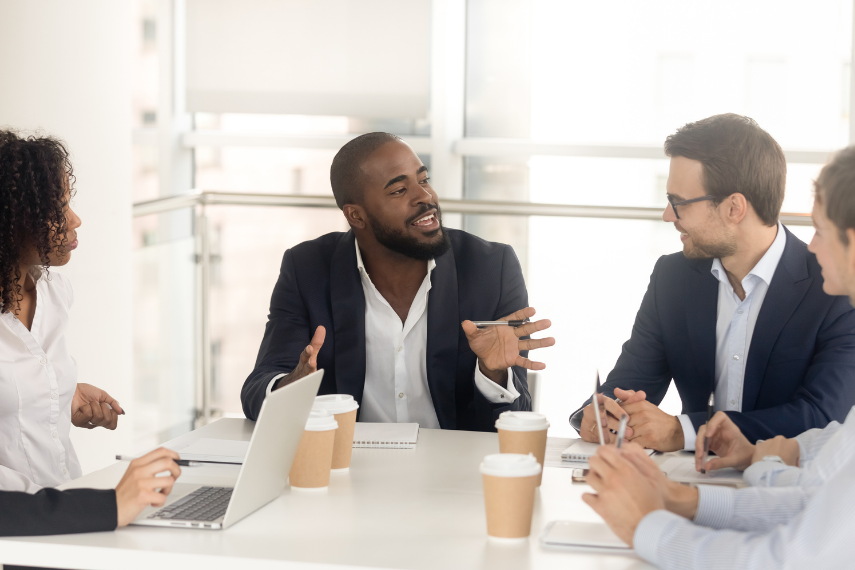 a group of people sitting at a table talking to each other