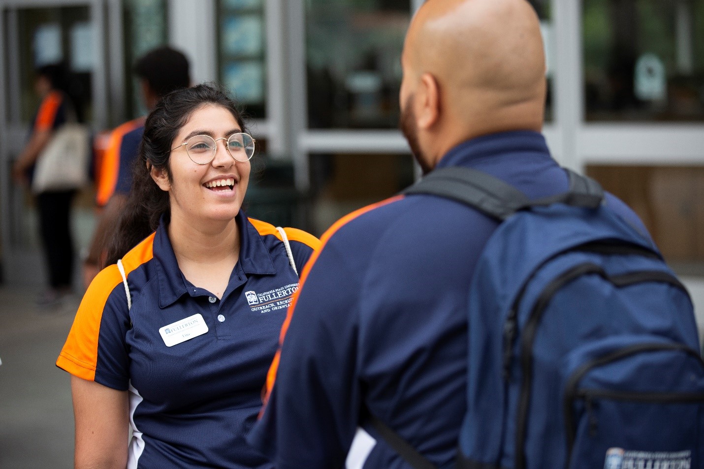 female student assistent smiling and talking to male student assistant