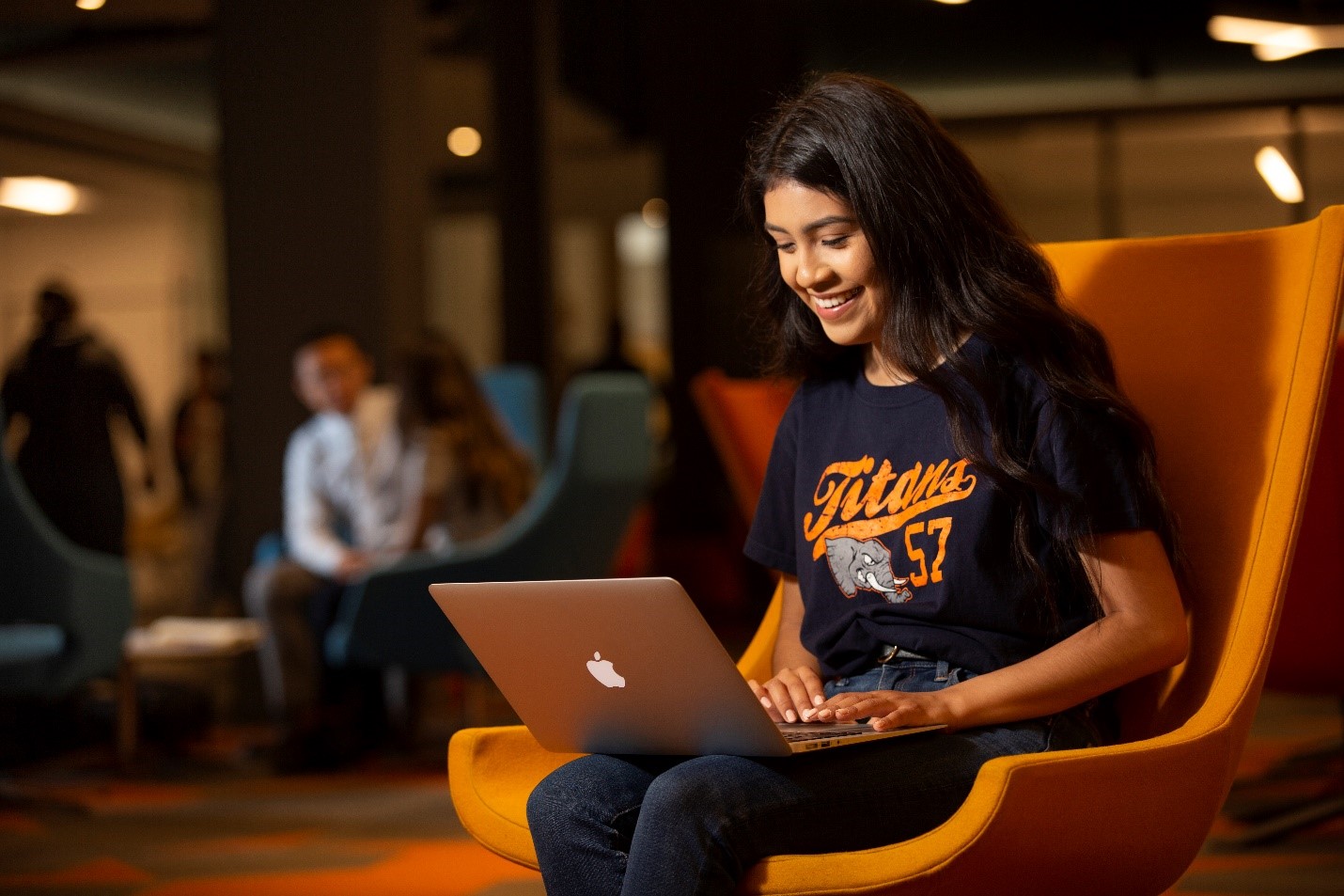 a female student smiling while looking at a laptop