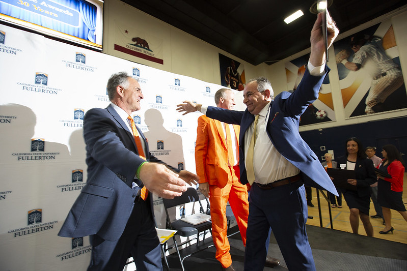 Employee greets President Virjee on stage at University Awards Program