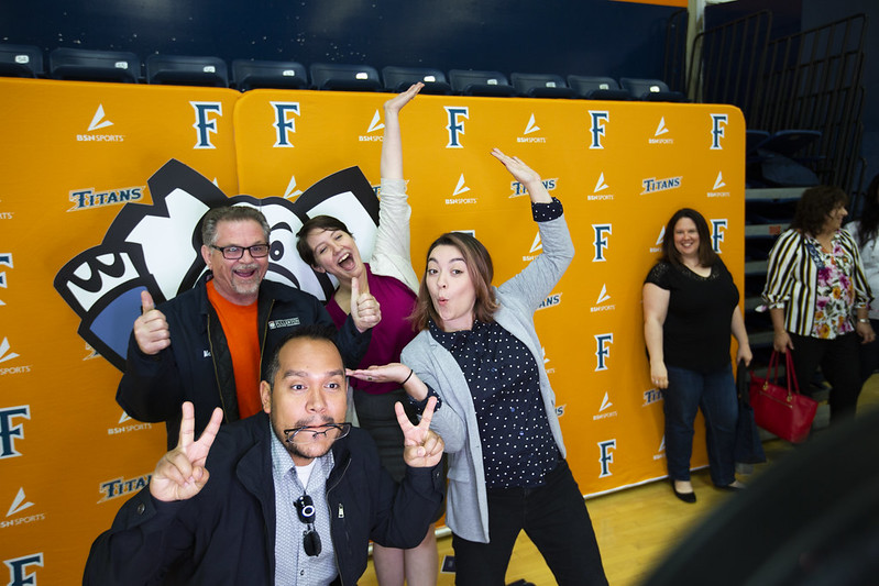 Employees pose in front of an orange photo backdrop at UAP.